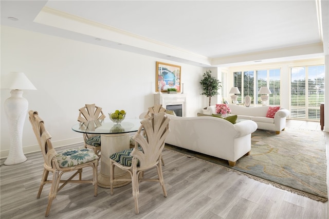 living room with a raised ceiling, light wood-type flooring, and ornamental molding