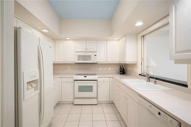 kitchen with tasteful backsplash, white cabinetry, sink, and white appliances