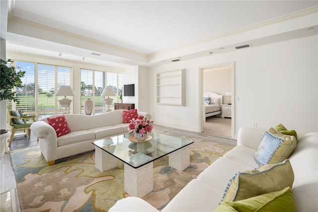 living room featuring built in shelves, light hardwood / wood-style floors, and ornamental molding