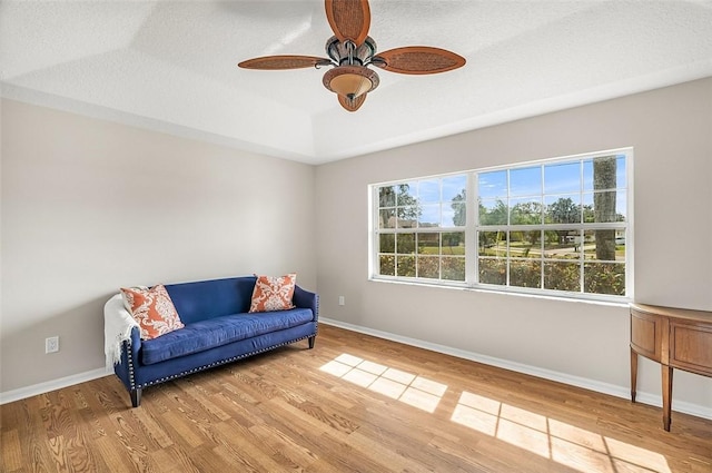 sitting room featuring ceiling fan, a tray ceiling, light hardwood / wood-style flooring, and a textured ceiling