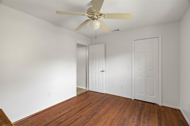 unfurnished bedroom with dark hardwood / wood-style flooring, a closet, and ceiling fan