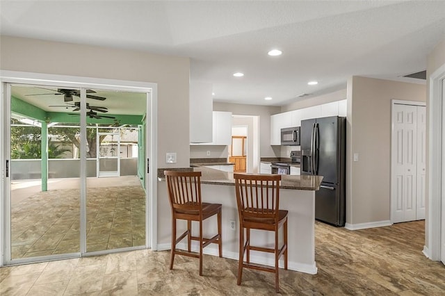 kitchen with ceiling fan, a kitchen breakfast bar, stainless steel appliances, white cabinets, and kitchen peninsula