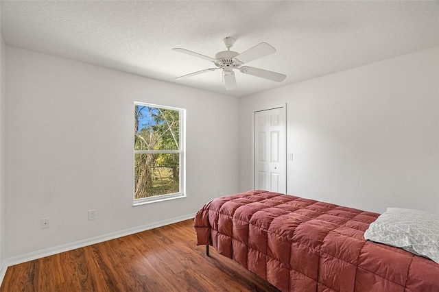 bedroom with ceiling fan, hardwood / wood-style flooring, and a textured ceiling