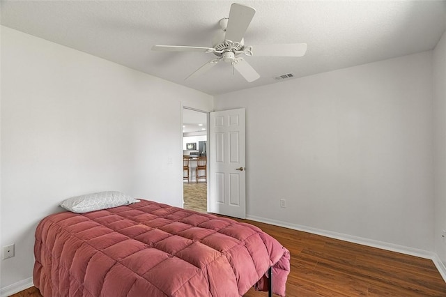 bedroom with dark hardwood / wood-style flooring, a textured ceiling, and ceiling fan