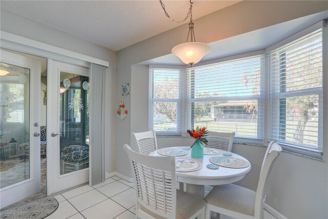 dining area with a wealth of natural light, baseboards, a textured ceiling, and light tile patterned floors