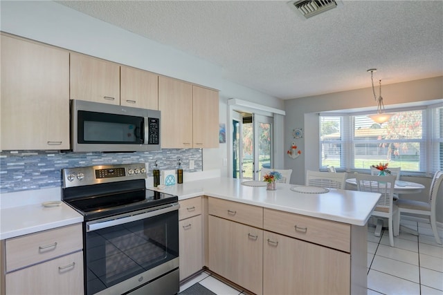 kitchen with stainless steel appliances, a peninsula, light brown cabinetry, and light countertops
