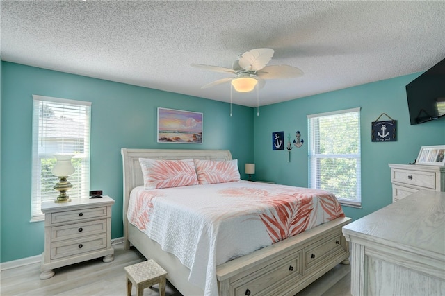 bedroom with baseboards, a textured ceiling, ceiling fan, and light wood finished floors