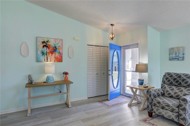 entrance foyer featuring a textured ceiling, baseboards, and wood finished floors