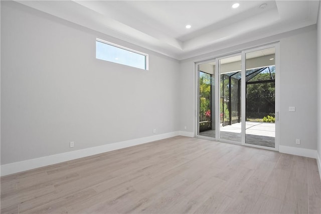 129 Strand Dr, Vero Beach, FL 32963 - unfurnished room featuring light wood-style floors, baseboards, a tray ceiling, and a wealth of natural light