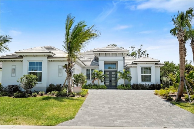 129 Strand Dr, Vero Beach, FL 32963 - view of front of property with french doors, stucco siding, a tile roof, and a front yard