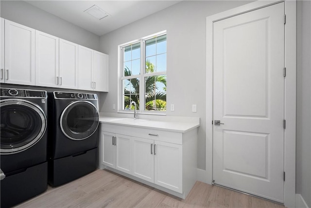 129 Strand Dr, Vero Beach, FL 32963 - clothes washing area featuring a sink, cabinet space, washing machine and dryer, and light wood-style flooring