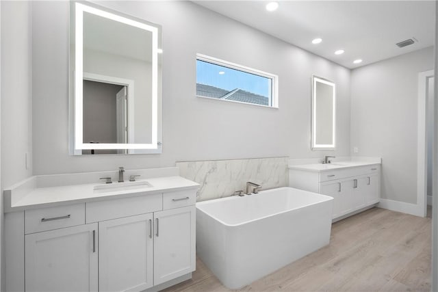 129 Strand Dr, Vero Beach, FL 32963 - bathroom featuring a sink, recessed lighting, two vanities, wood finished floors, and visible vents