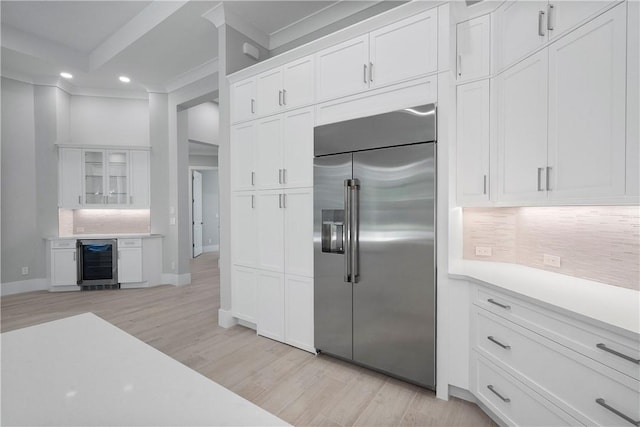 129 Strand Dr, Vero Beach, FL 32963 - kitchen with wine cooler, recessed lighting, stainless steel built in fridge, white cabinets, and backsplash