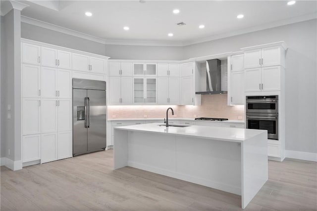 129 Strand Dr, Vero Beach, FL 32963 - kitchen with crown molding, a sink, wall chimney exhaust hood, stainless steel appliances, and white cabinetry