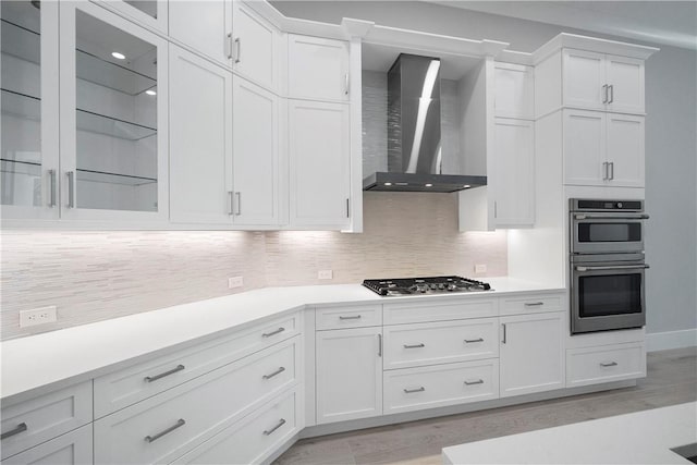 129 Strand Dr, Vero Beach, FL 32963 - kitchen featuring light countertops, stainless steel appliances, light wood finished floors, and wall chimney exhaust hood