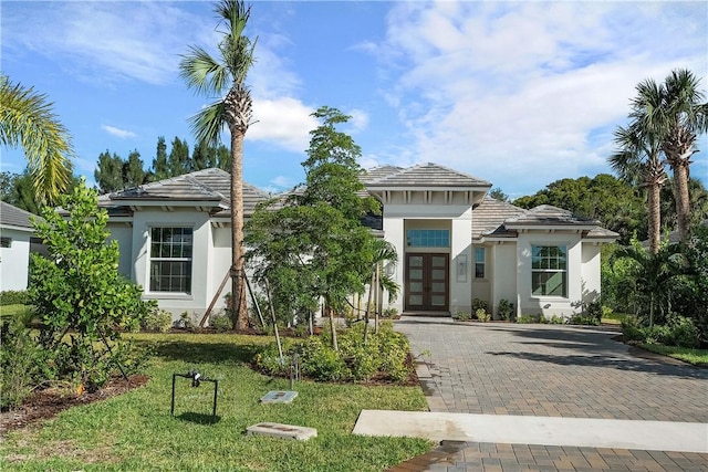 mediterranean / spanish-style house featuring a front lawn and french doors