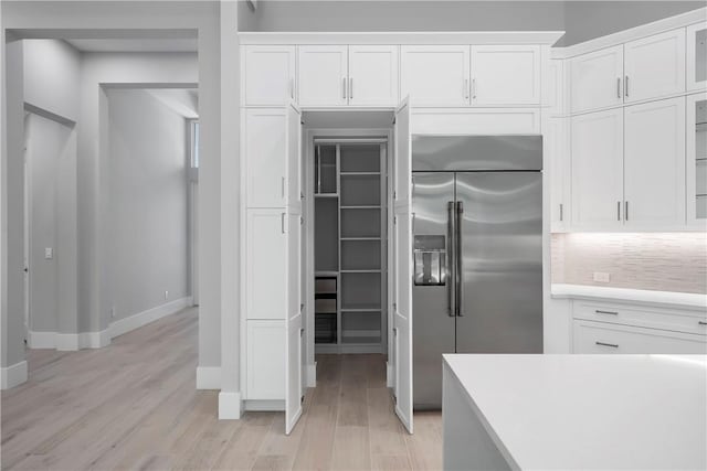 129 Strand Dr, Vero Beach, FL 32963 - kitchen with white cabinets, baseboards, stainless steel built in fridge, and light wood-style flooring