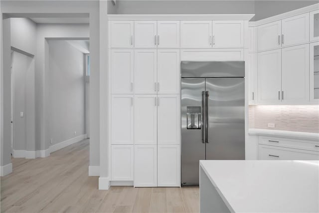 129 Strand Dr, Vero Beach, FL 32963 - kitchen with white cabinets, stainless steel built in refrigerator, and light wood finished floors