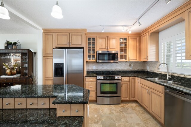 kitchen with stainless steel appliances, hanging light fixtures, sink, and dark stone countertops