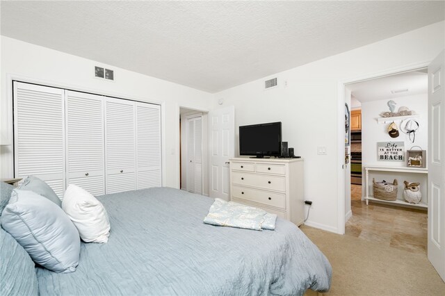 bedroom with a textured ceiling, light carpet, and a closet