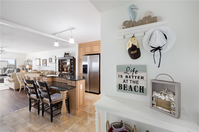 kitchen with light wood-type flooring, stainless steel fridge with ice dispenser, a kitchen bar, pendant lighting, and a center island