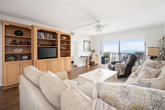 living room featuring ceiling fan, dark hardwood / wood-style floors, and a textured ceiling