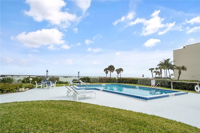 view of pool with a patio area and a lawn