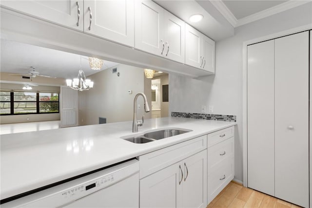 kitchen with ornamental molding, a sink, white cabinetry, light countertops, and dishwasher