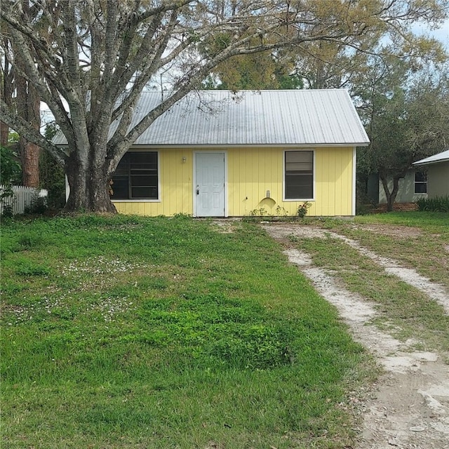 exterior space with driveway, metal roof, and a front yard