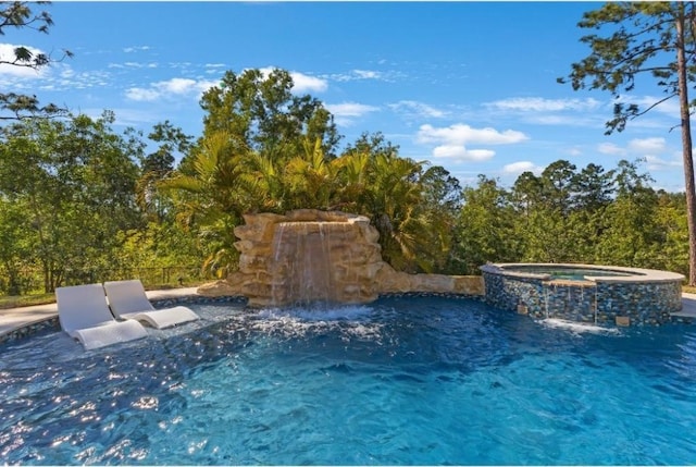 view of pool with an in ground hot tub and pool water feature