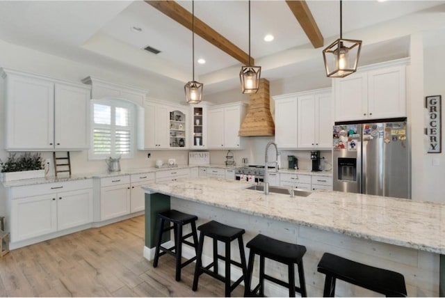 kitchen with stainless steel refrigerator with ice dispenser, light stone countertops, hanging light fixtures, and white cabinets