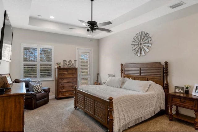 carpeted bedroom with ceiling fan and a tray ceiling