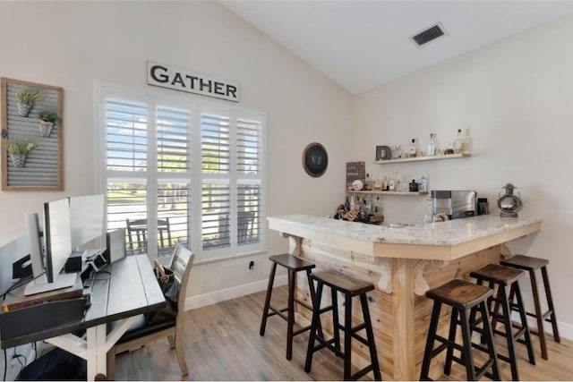 bar featuring vaulted ceiling and light wood-type flooring