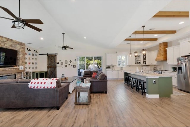 living room with ceiling fan, a barn door, sink, and light hardwood / wood-style flooring