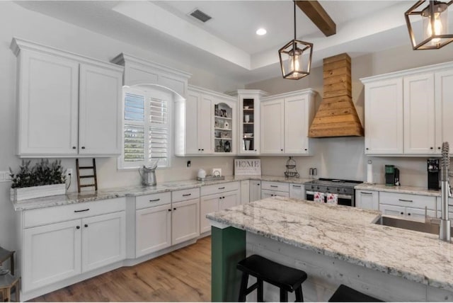 kitchen featuring custom exhaust hood, white cabinetry, and decorative light fixtures