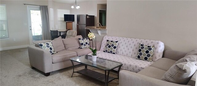 living room with light carpet, baseboards, and an inviting chandelier