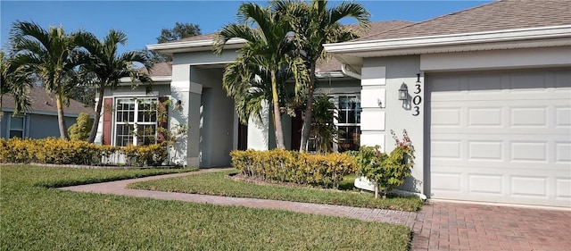 doorway to property with stucco siding, a garage, roof with shingles, and a lawn