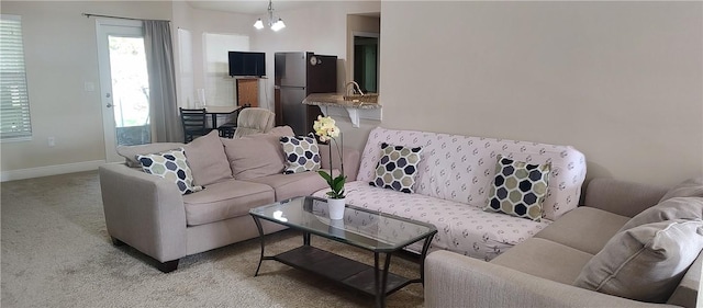 living room with light colored carpet, baseboards, and an inviting chandelier