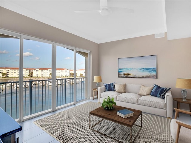 living room with ceiling fan, a water view, and light tile patterned floors