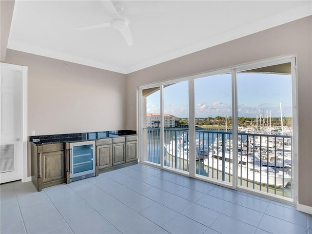 interior space with light tile patterned floors, a water view, ceiling fan, and beverage cooler