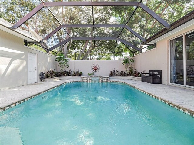 view of swimming pool with glass enclosure, an in ground hot tub, and a patio area