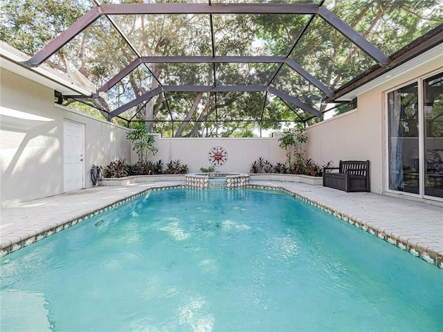 view of swimming pool with a patio area, glass enclosure, and a pool with connected hot tub