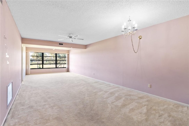 carpeted empty room featuring a textured ceiling and ceiling fan with notable chandelier