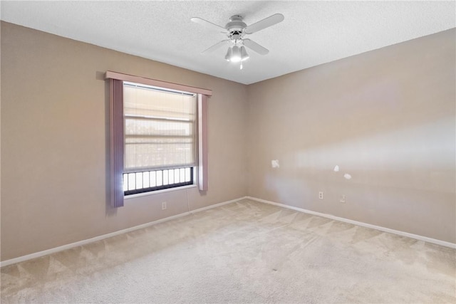 empty room featuring a textured ceiling, light colored carpet, ceiling fan, and a healthy amount of sunlight