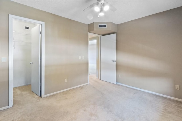 unfurnished bedroom with ceiling fan, a closet, a spacious closet, and light carpet