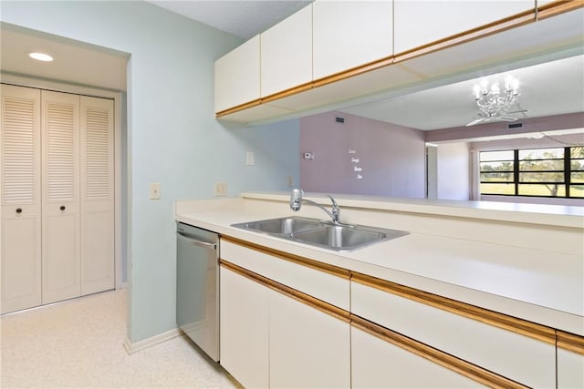 kitchen featuring kitchen peninsula, stainless steel dishwasher, sink, white cabinets, and a chandelier