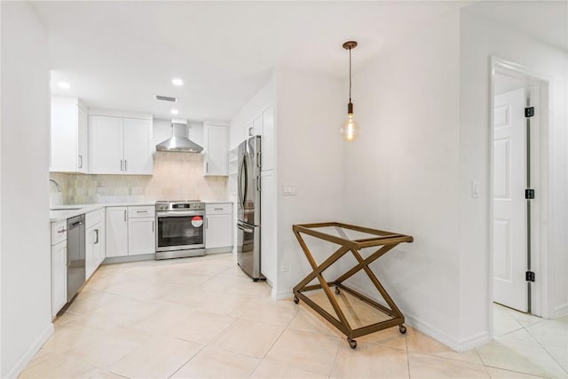 kitchen with white cabinetry, hanging light fixtures, stainless steel appliances, and wall chimney exhaust hood