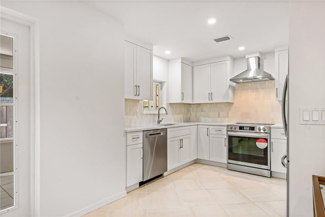 kitchen with stainless steel appliances, white cabinets, wall chimney range hood, backsplash, and sink