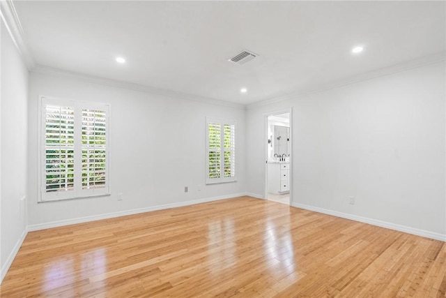 empty room with crown molding and light hardwood / wood-style floors