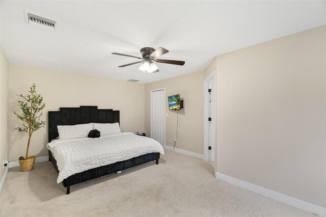 bedroom with a closet, light colored carpet, visible vents, a ceiling fan, and baseboards